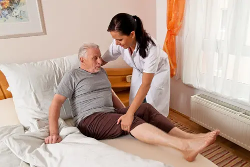 Pflegebedürftiger alter Mann bekommt unterstützung von Pflegerin